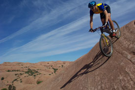 A man riding a mountain bike down a bolder